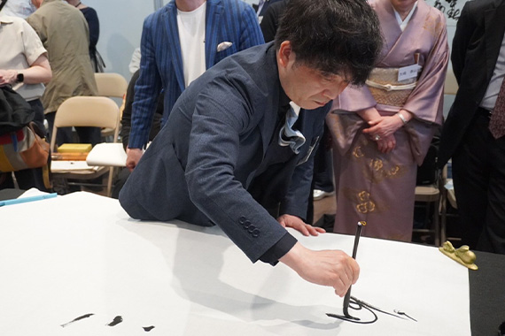 Associate Professor Fukui demonstrates his calligraphy at the Japan-China calligraphy exchange event at the Osaka-Kansai Expo